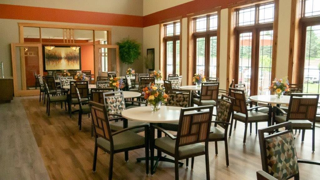 An elegantly designed dining room with multiple tables and chairs, illuminated by natural light from large windows.