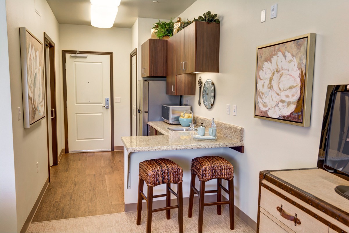 A modern apartment kitchen featuring a cozy countertop with bar stools and stylish decor.