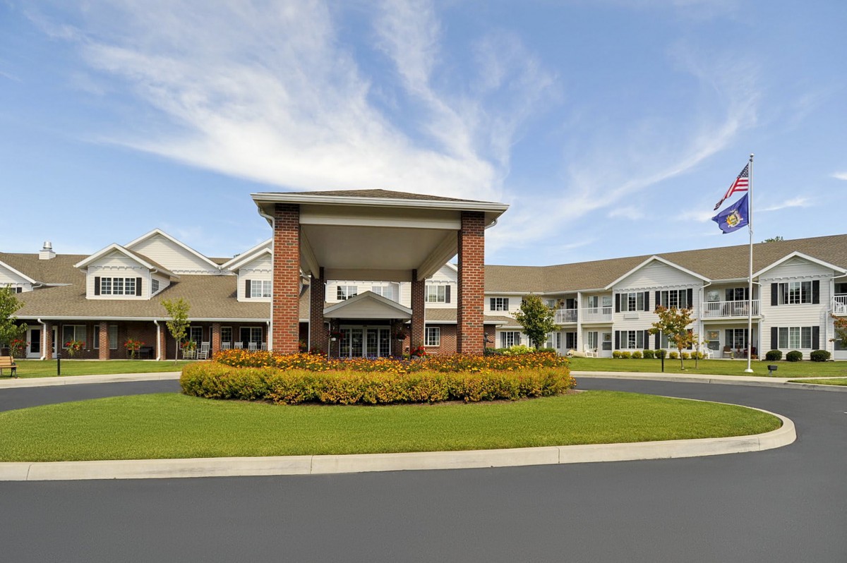 A modern residential building with a landscaped entrance and driveway.