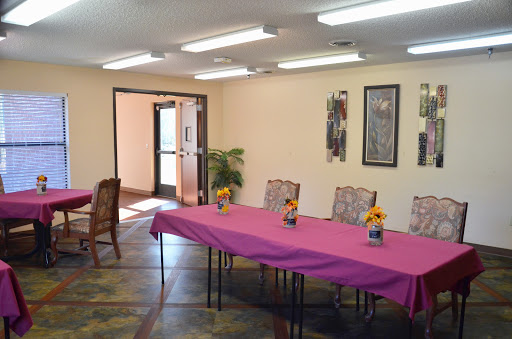 A well-lit meeting room set up for an event with a pink tablecloth and flower centerpieces.