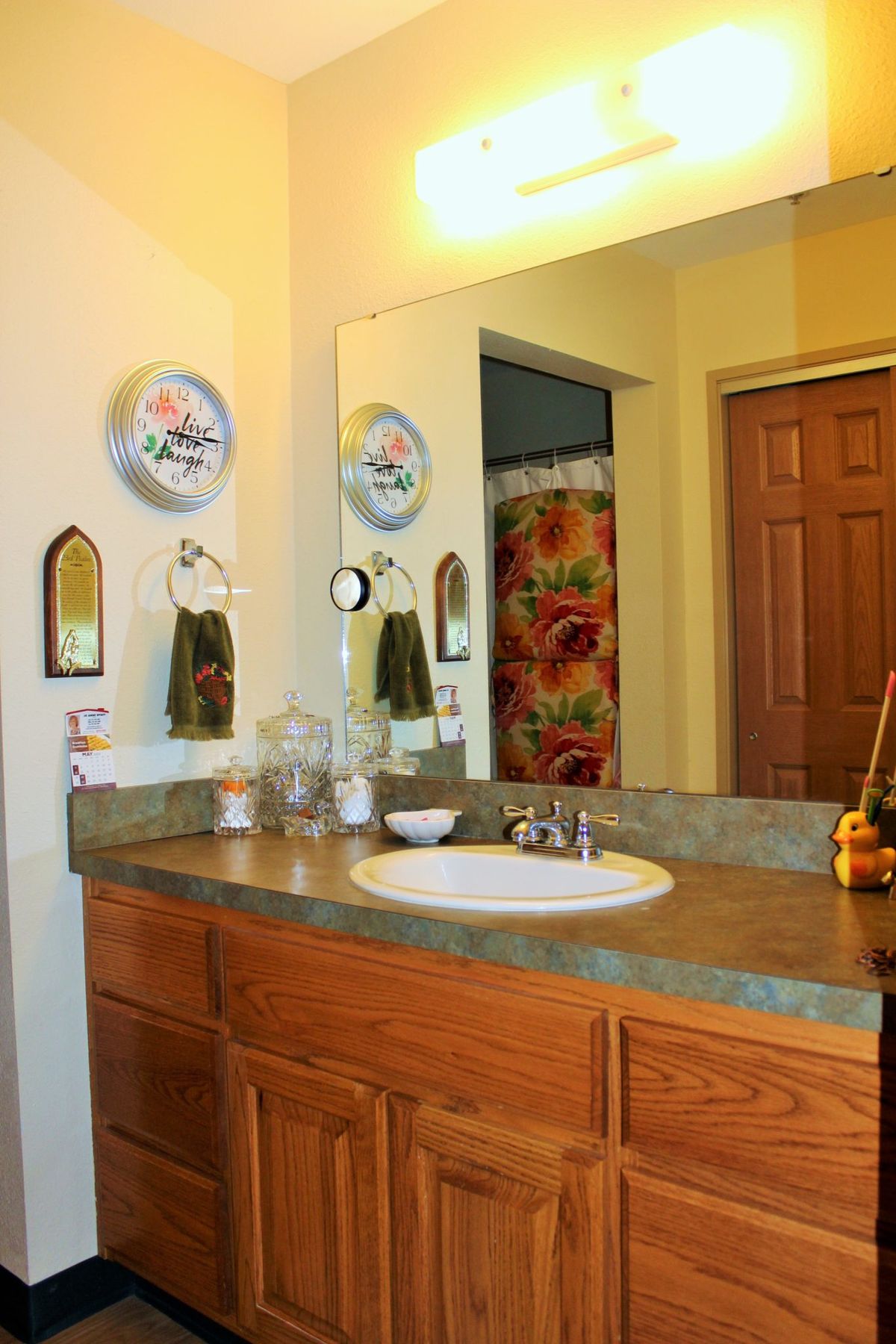 A cozy bathroom with a sink and mirror, colorful decor, and a shower curtain.