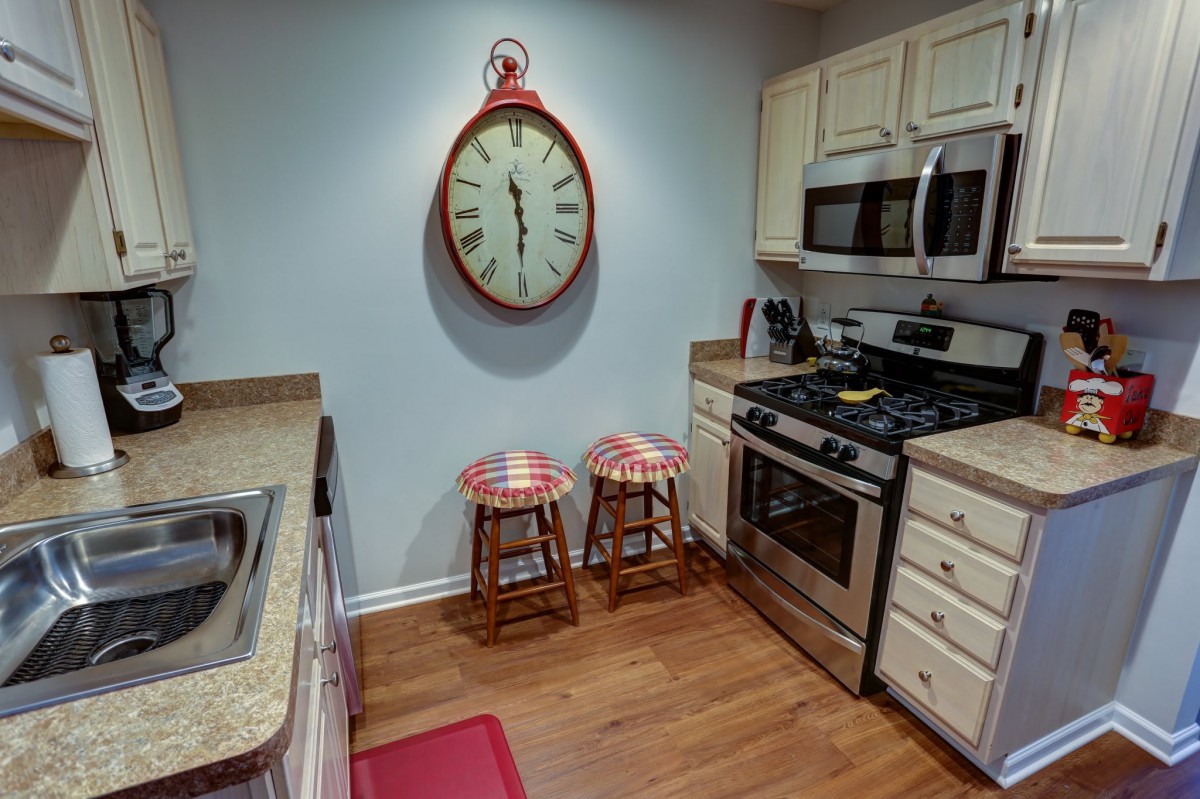 Cozy kitchen interior with a large wall clock and checkered stools.