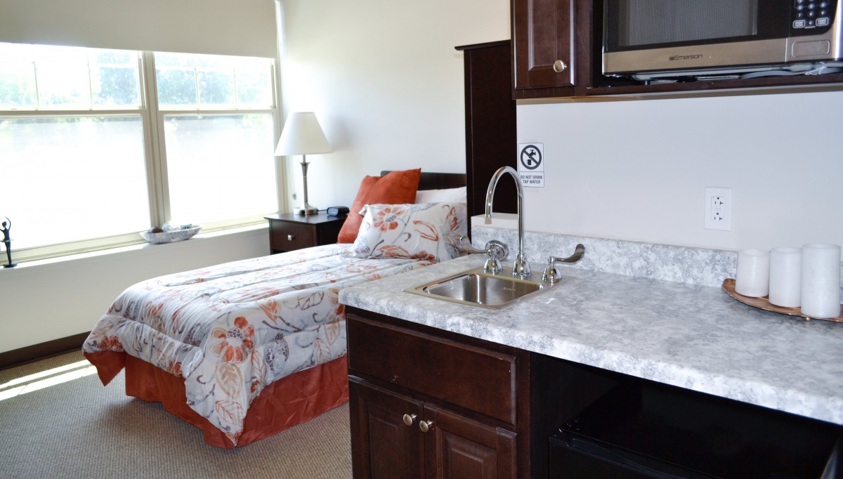 A cozy bedroom with a kitchenette and single bed.