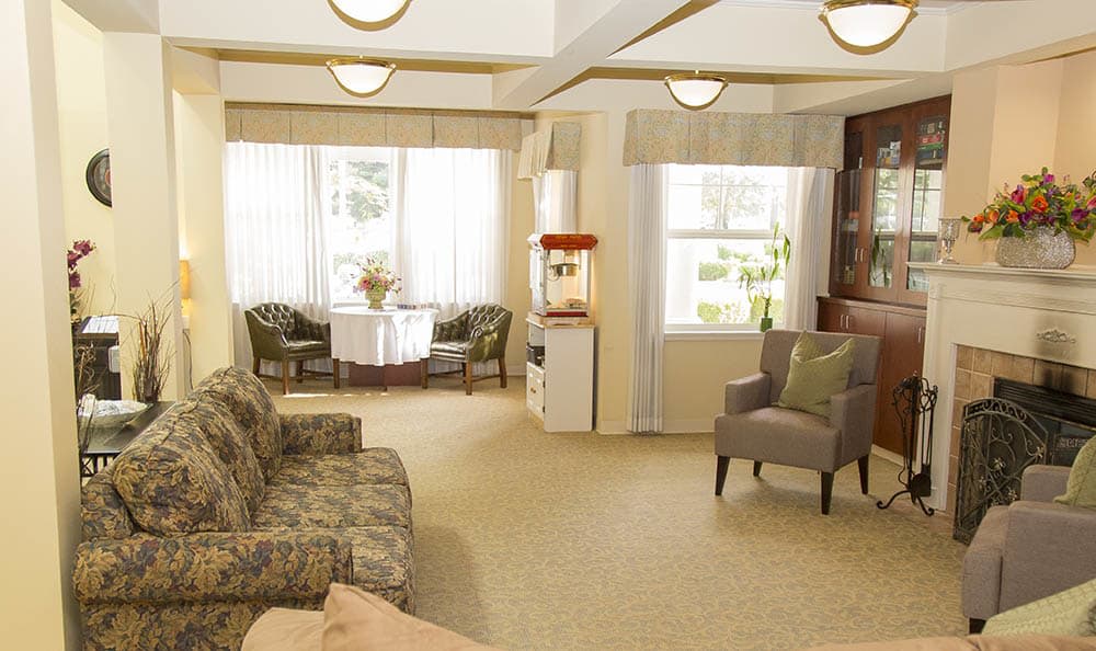 A cozy living room with comfortable seating, natural lighting, and a popcorn machine by the window.