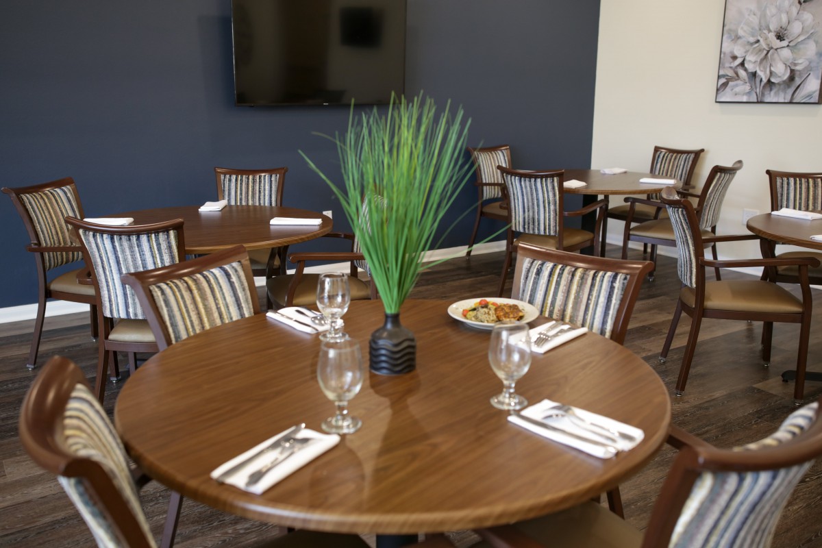 A neatly set dining table in a restaurant with glassware, cutlery, and a plant centerpiece.