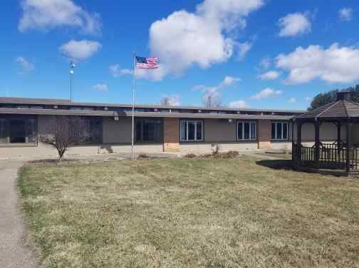A school building with an American flag flying under a partly cloudy sky.