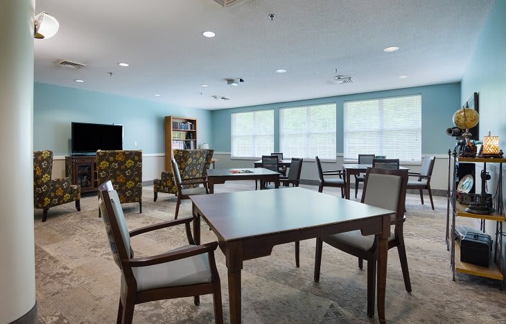 A bright and spacious room with tables and chairs arranged in a communal setting.