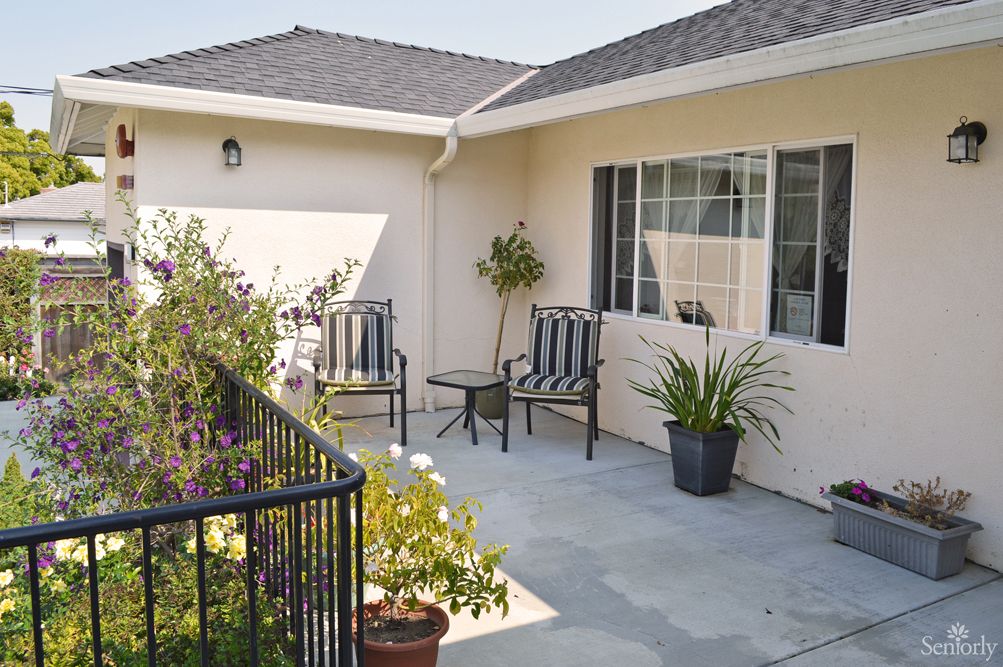 A cozy patio with chairs, a table, and potted plants.