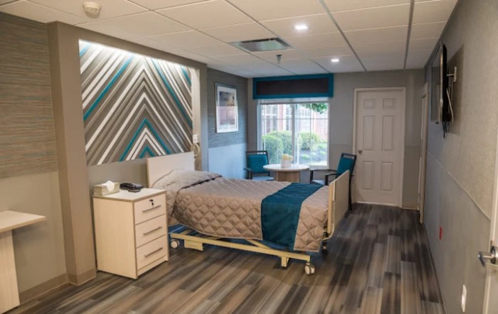 A modern hospital room with a single bed, nightstand, and contemporary decor.
