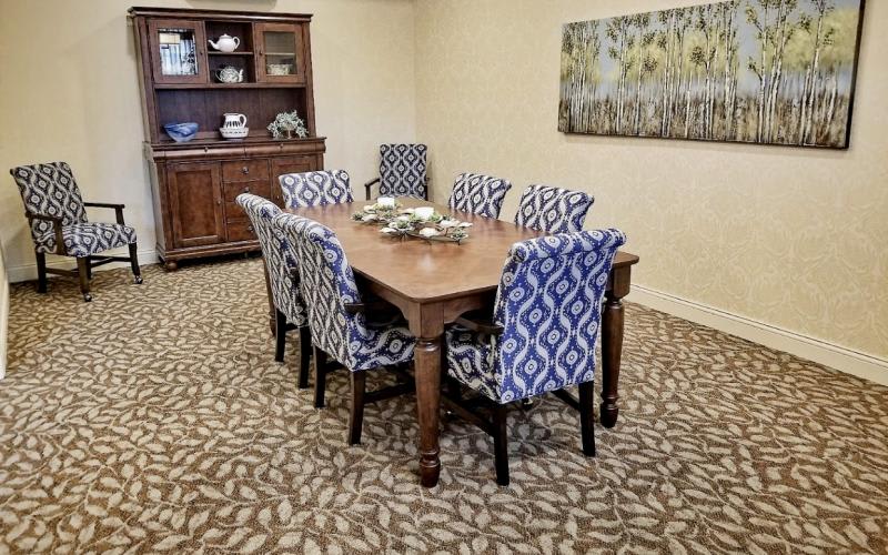 A dining room setup with a wooden table, patterned chairs, and a decorative carpet.
