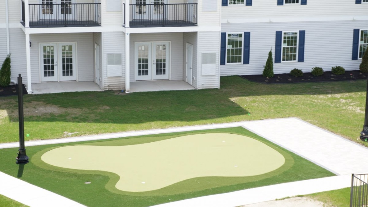 A residential building with a small putting green in the front yard.