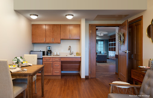 A modern kitchen featuring wooden cabinets, a dining area, and contemporary appliances.
