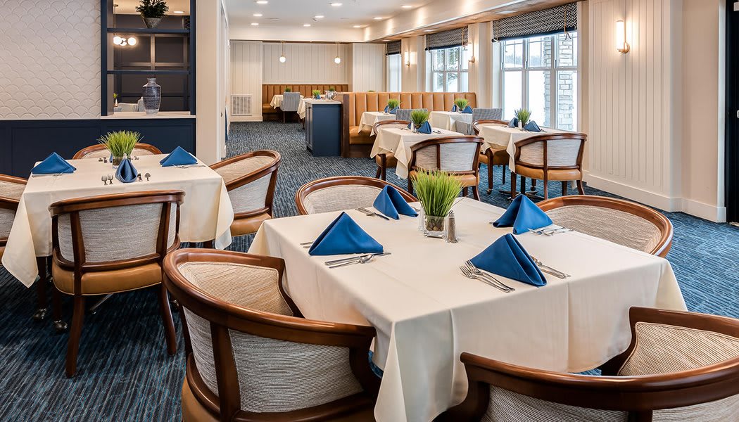 An elegant dining area with neatly arranged tables and blue napkins.