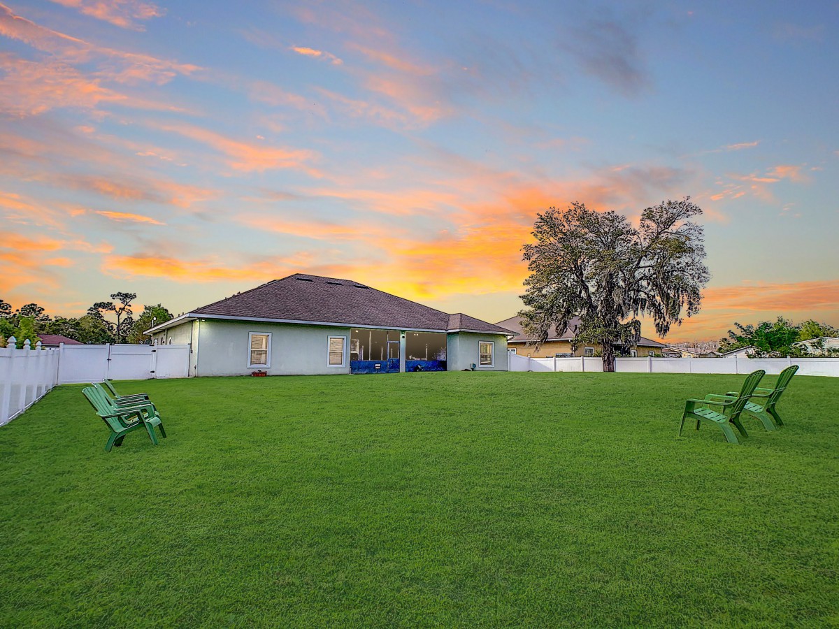 A tranquil backyard with a single-story house and a vibrant sunset sky.