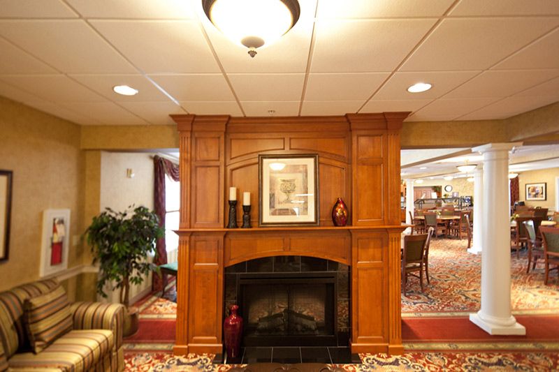 A cozy living area featuring a wooden fireplace adorned with artwork and candle holders.