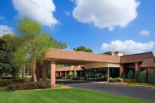 A modern brick building under a blue sky with scattered clouds, featuring a well-maintained lawn and driveway.