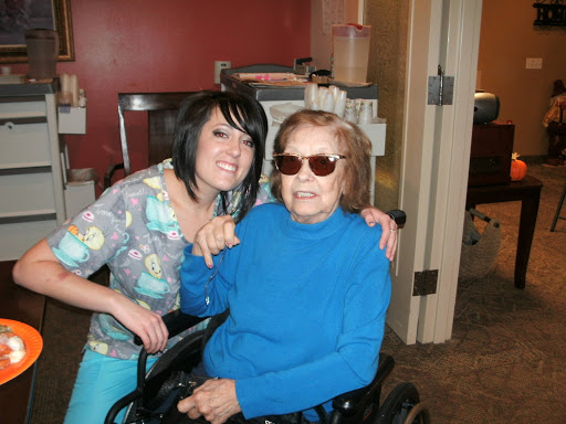 A joyful moment shared between a young caregiver and an elderly woman in a wheelchair.