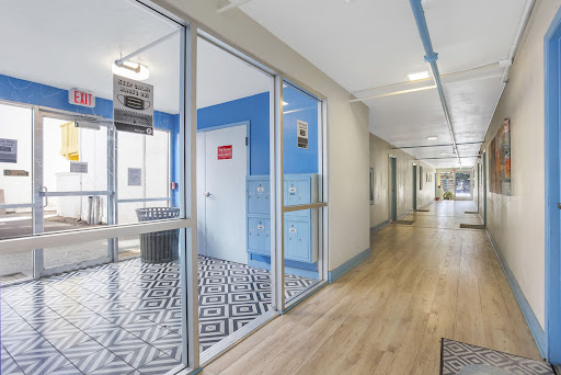 A modern office hallway featuring blue walls, wooden flooring, and geometric patterned tiles.