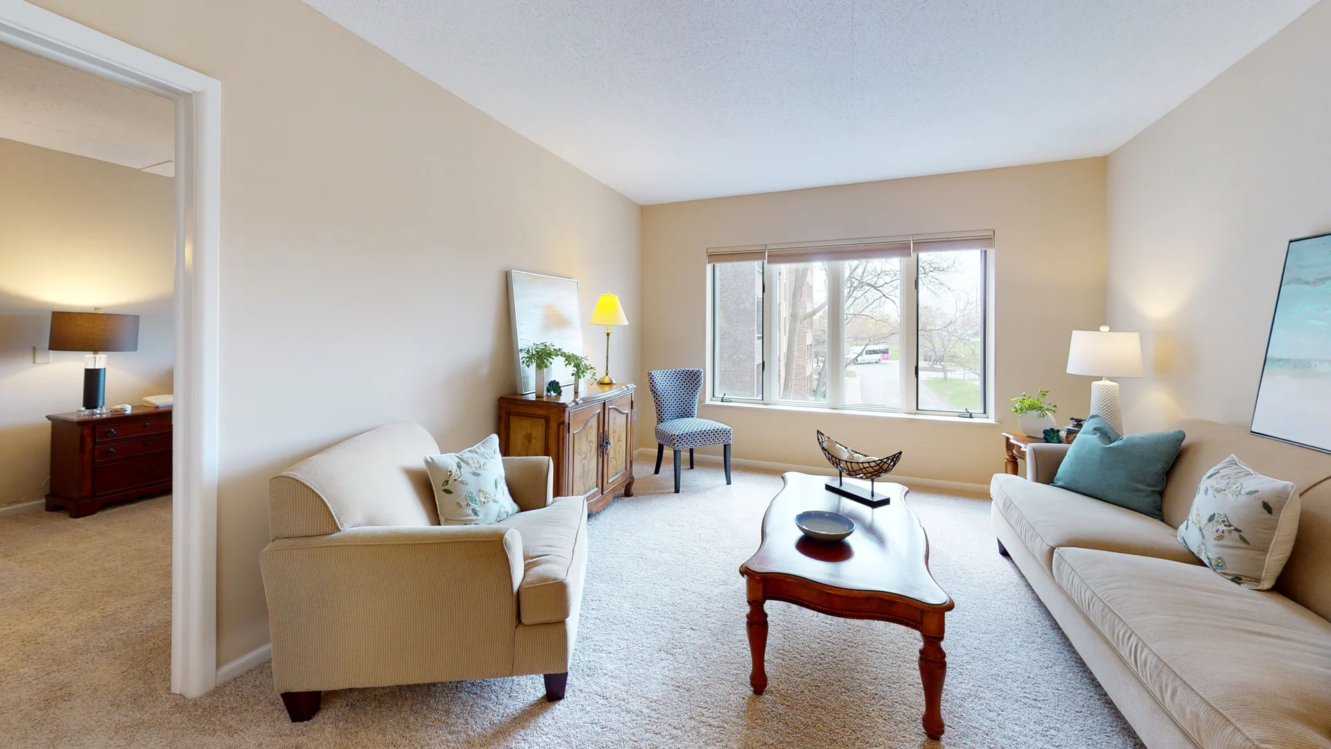 A cozy living room with comfortable sofas, a wooden coffee table, and large windows allowing natural light.