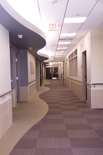 A well-lit and clean hospital hallway with a curved design.