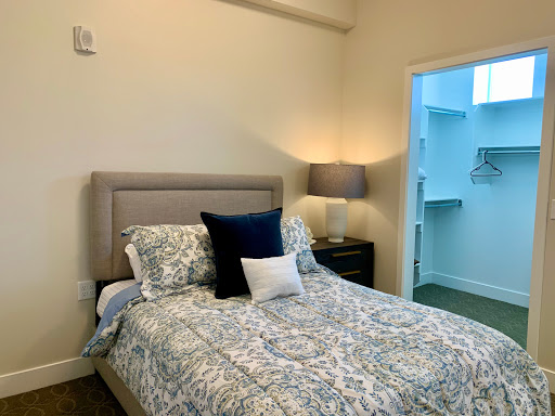 A cozy and inviting bedroom featuring a neatly made bed with decorative pillows and a stylish lamp.