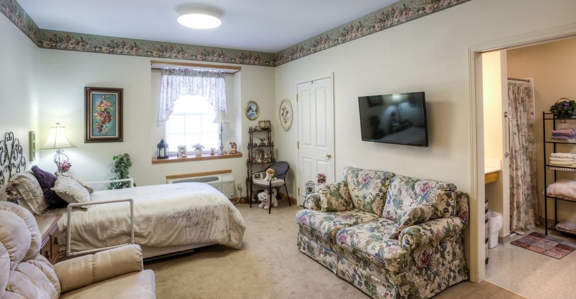 A cozy bedroom with floral furniture and a television.