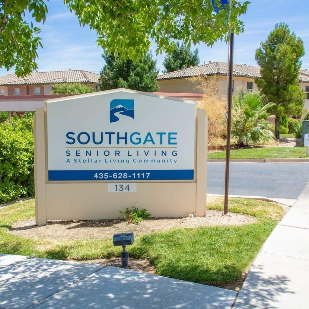 An outdoor sign for Southgate Senior Living surrounded by trees and a sidewalk.