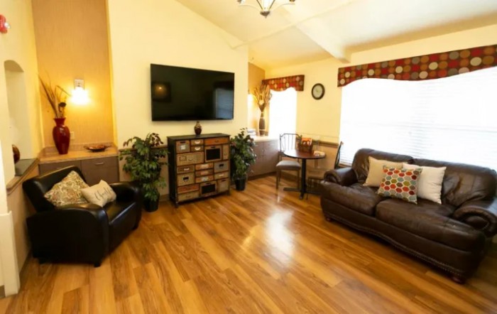 A cozy living room with comfortable seating and a flat-screen TV on the wall.