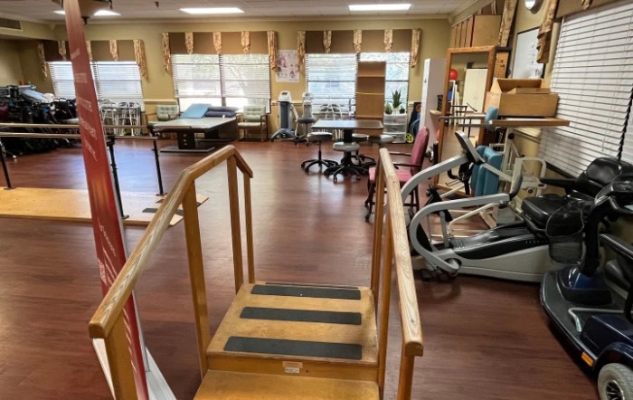 A rehabilitation center with various therapy and exercise equipment arranged in a spacious room.