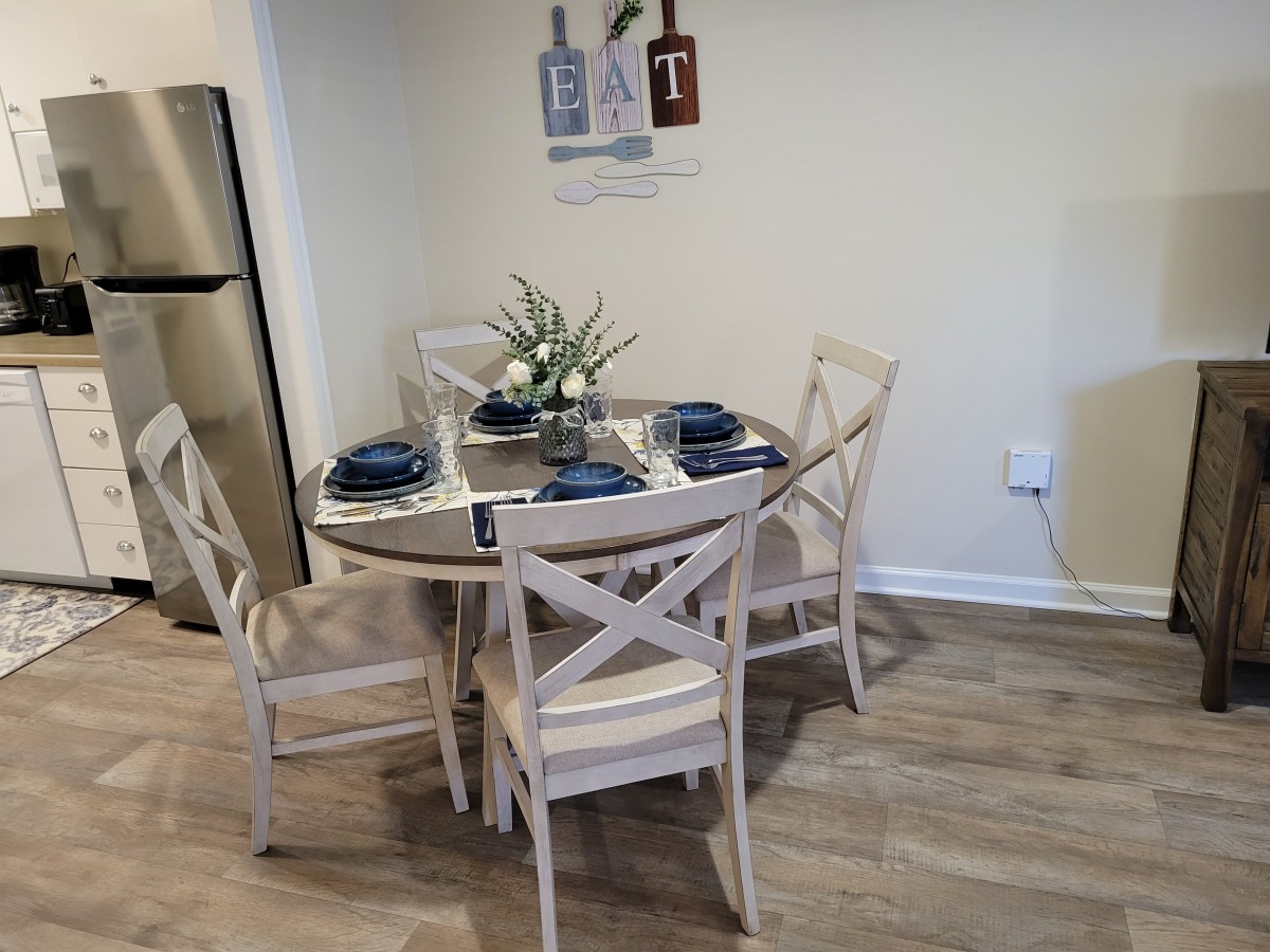 A cozy dining area featuring a round table set with blue napkins and elegant dinnerware.