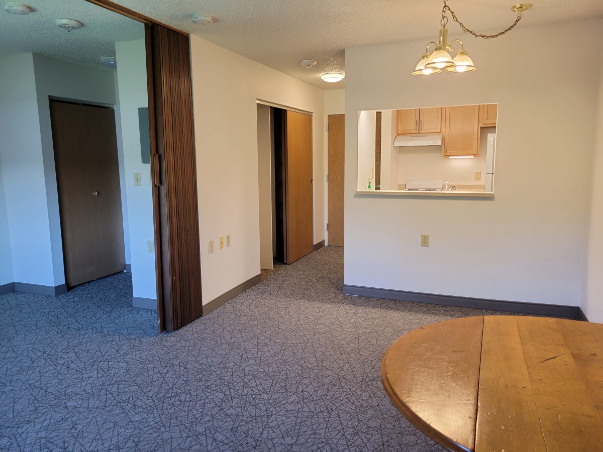 An empty apartment interior with an open kitchen and dining area.