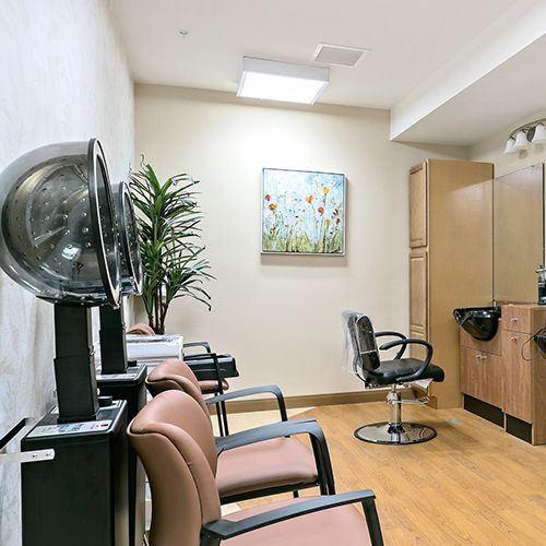 A modern hair salon interior with styling chairs, a dryer, and wall art.