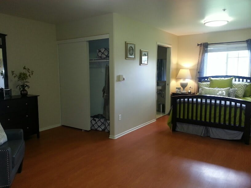 A spacious bedroom with a crib, hardwood flooring, and ample natural light.