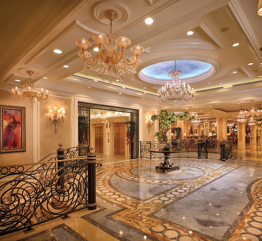A luxurious hotel lobby featuring ornate chandeliers, a marble floor, and an elegant design.