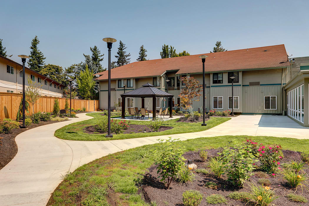 A modern building with a landscaped garden and winding pathways under clear skies.