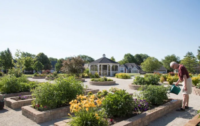 A beautiful garden with vibrant flowers and a central pavilion under a clear blue sky.