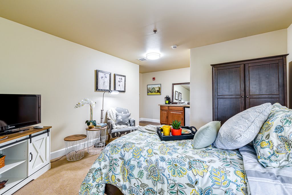 A cozy bedroom with floral bedding, decorated with elegant furniture and soft lighting.