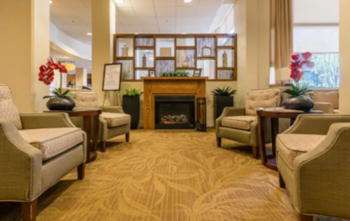 A cozy hotel lobby with comfortable seating around a fireplace.