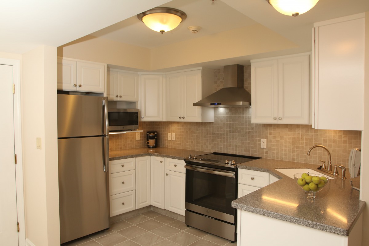 A modern kitchen featuring stainless steel appliances and white cabinetry.