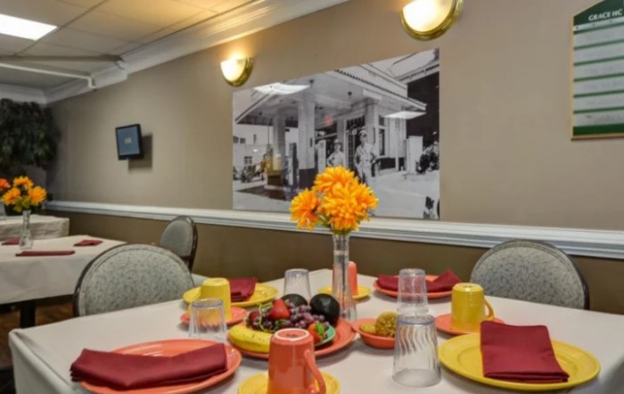 A neatly set dining table with colorful tableware and a vase of yellow flowers.