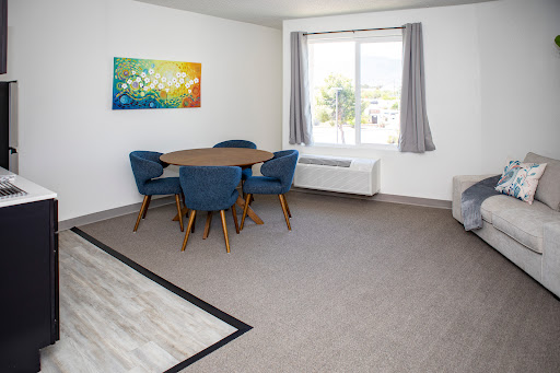 A bright and modern dining area featuring a round table and blue chairs, complemented by an artistic wall decoration.