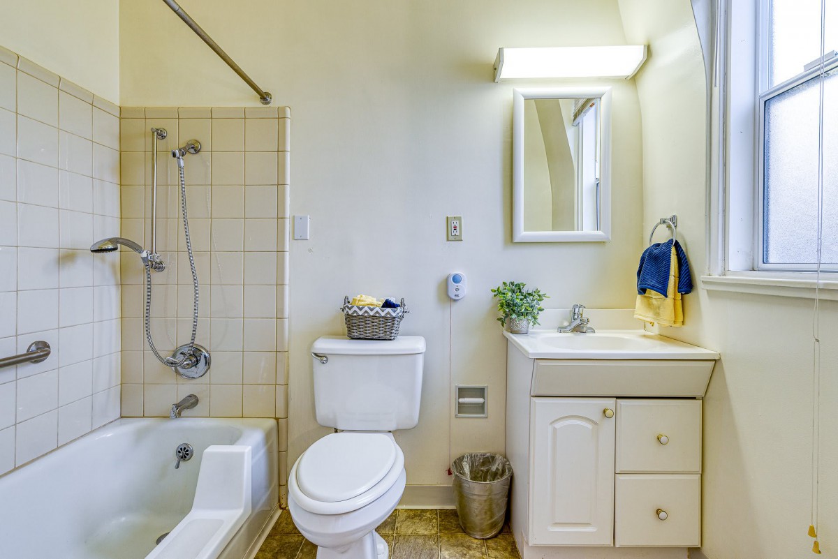 A bright and clean bathroom with essential amenities including a toilet, sink, mirror, bathtub, and shower.