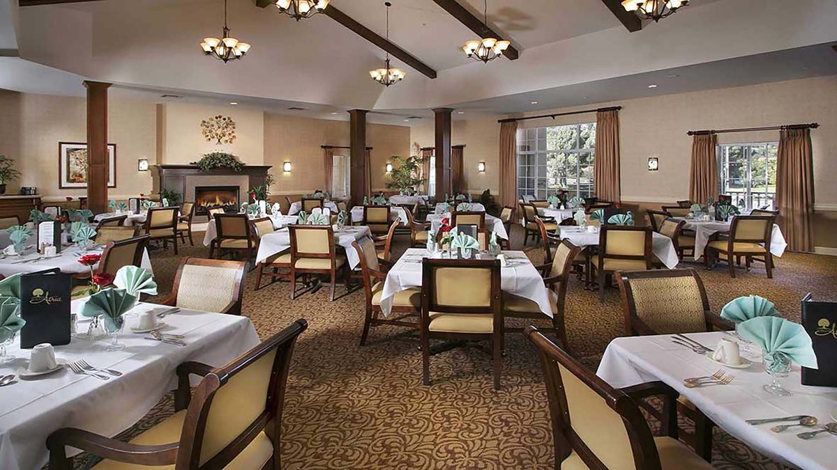 An elegant dining room with neatly arranged tables and chairs, adorned with chandeliers.