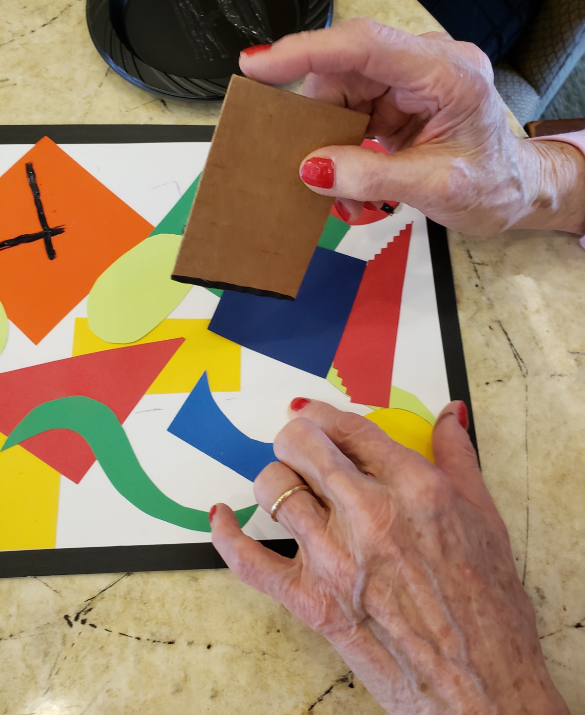 A person arranging colorful paper shapes on a table.