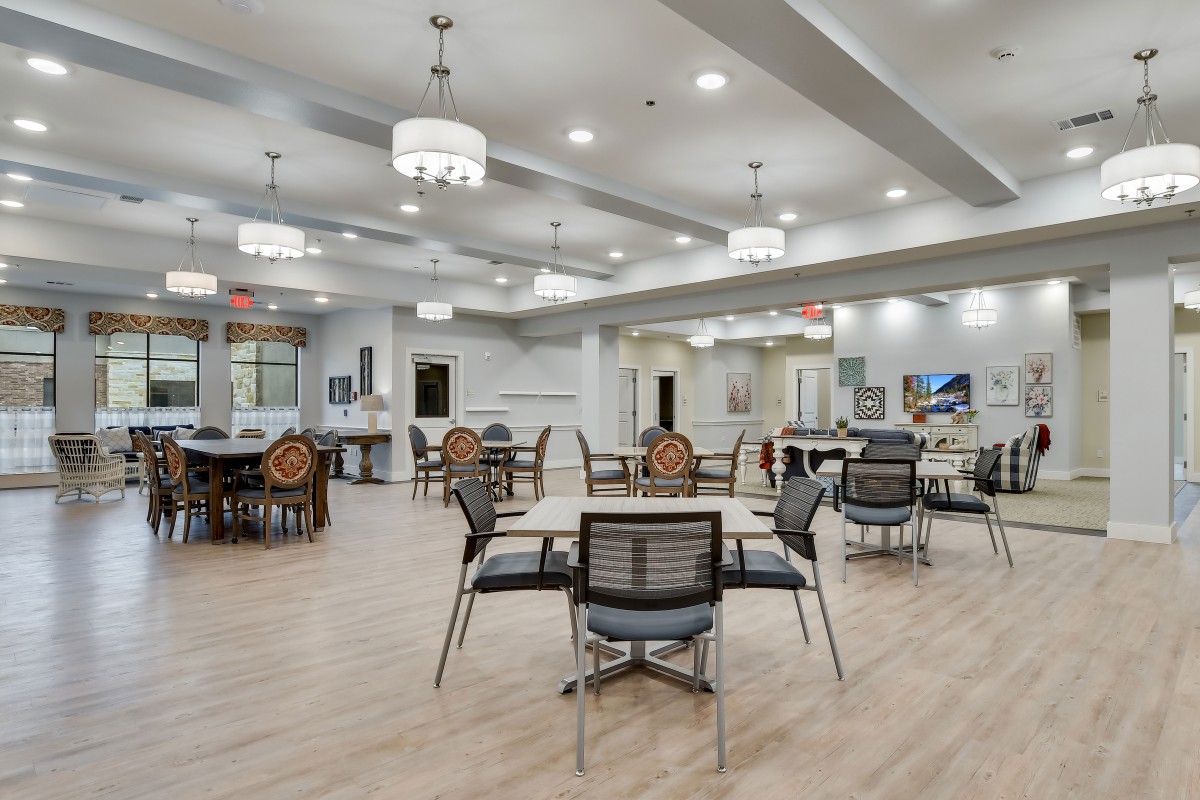 A spacious and modern dining area with elegant lighting and neatly arranged tables and chairs.