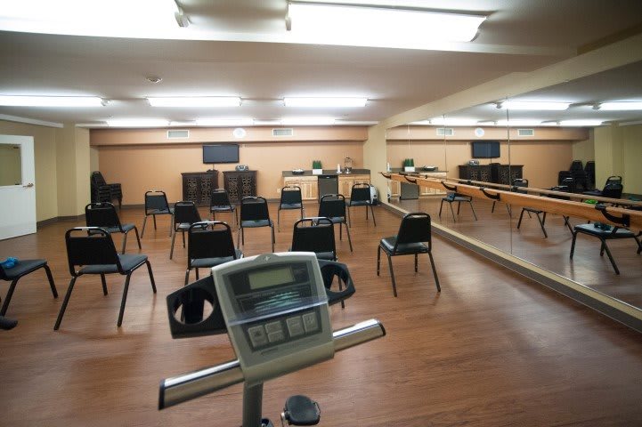 An exercise room with chairs arranged facing mirrors and screens.