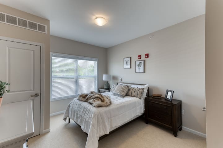 A cozy bedroom with a large window and neutral decor.