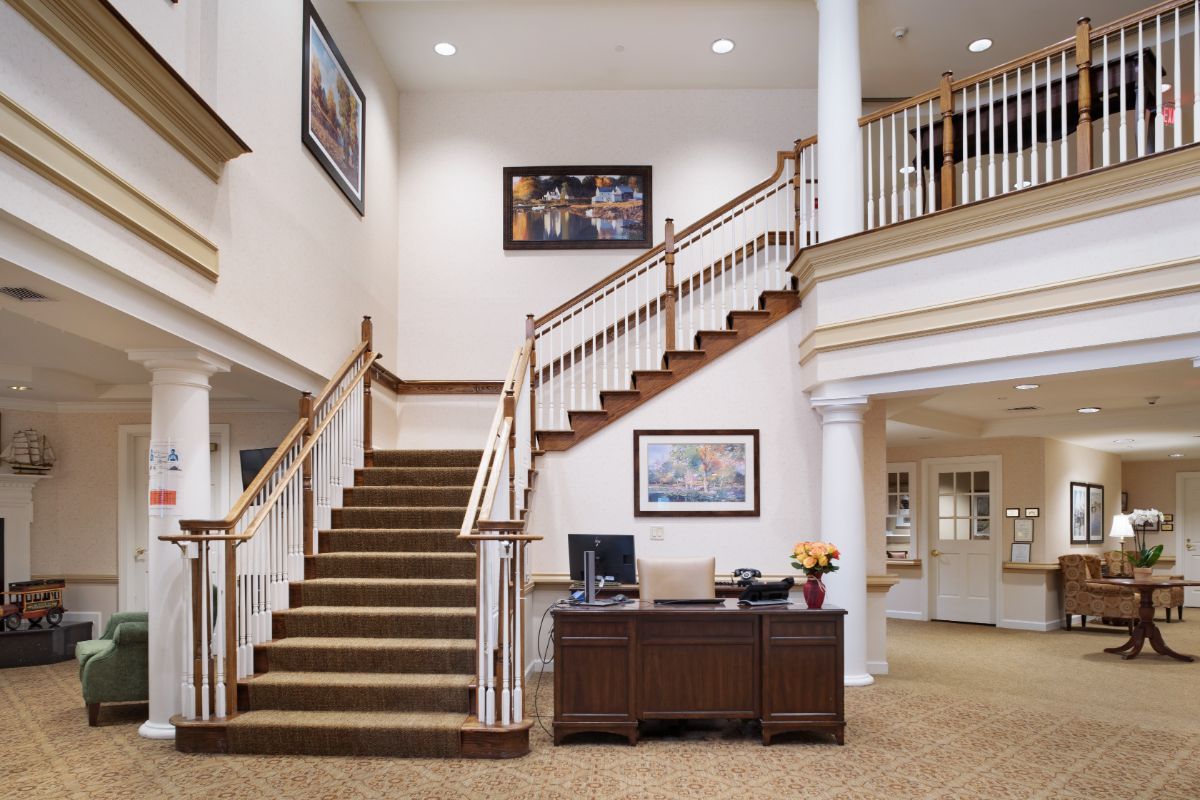 A spacious lobby area featuring a grand staircase, an office desk, and elegant decor.