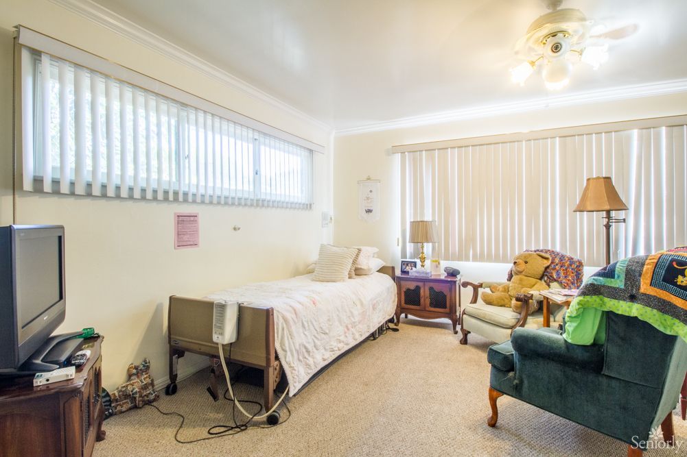 A hospital room with a bed, chairs, and medical equipment.