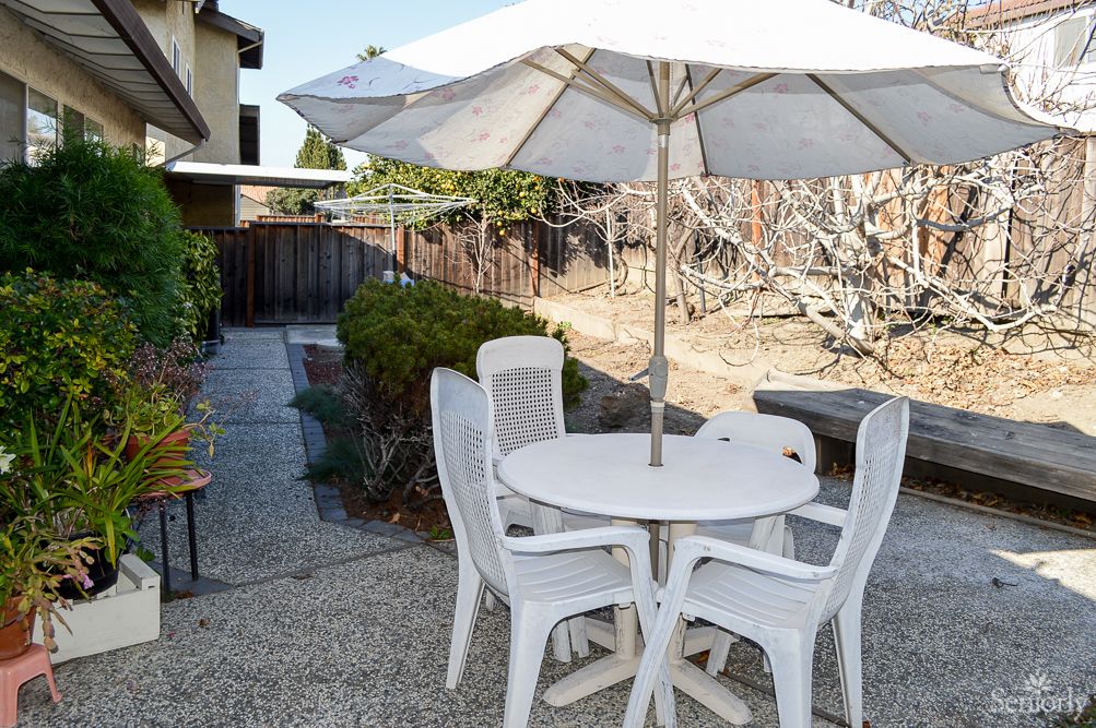 A patio area with a white table, chairs, and a large umbrella.